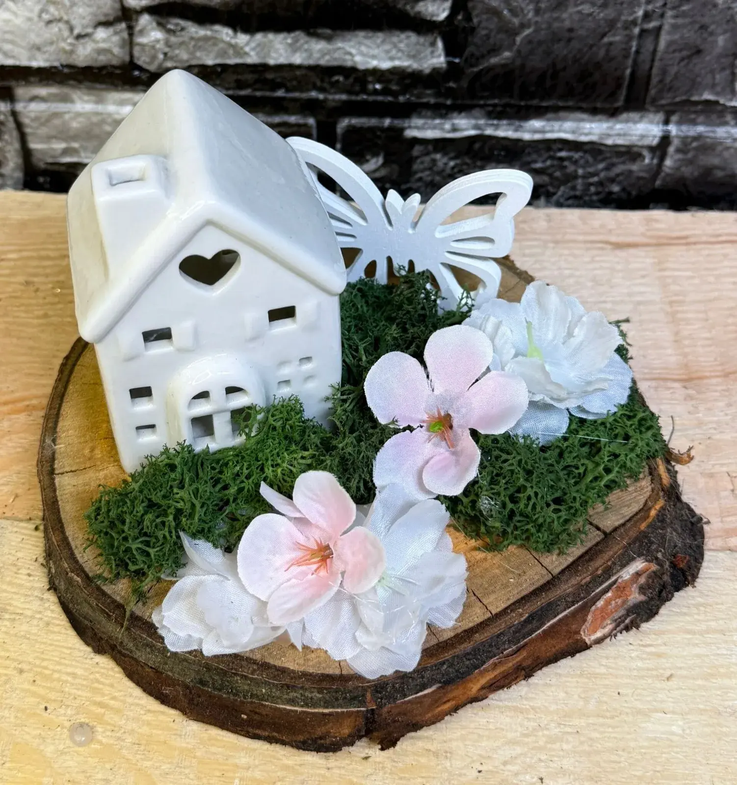 Frühlingsarrangement mit Keramikhaus und Blüten