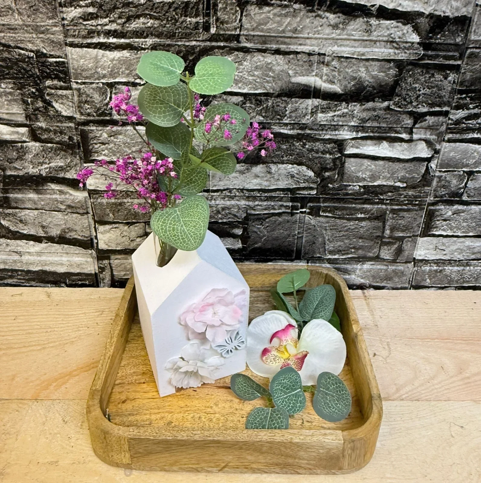 Frühlingsdekoration mit Hausvase und Blüten