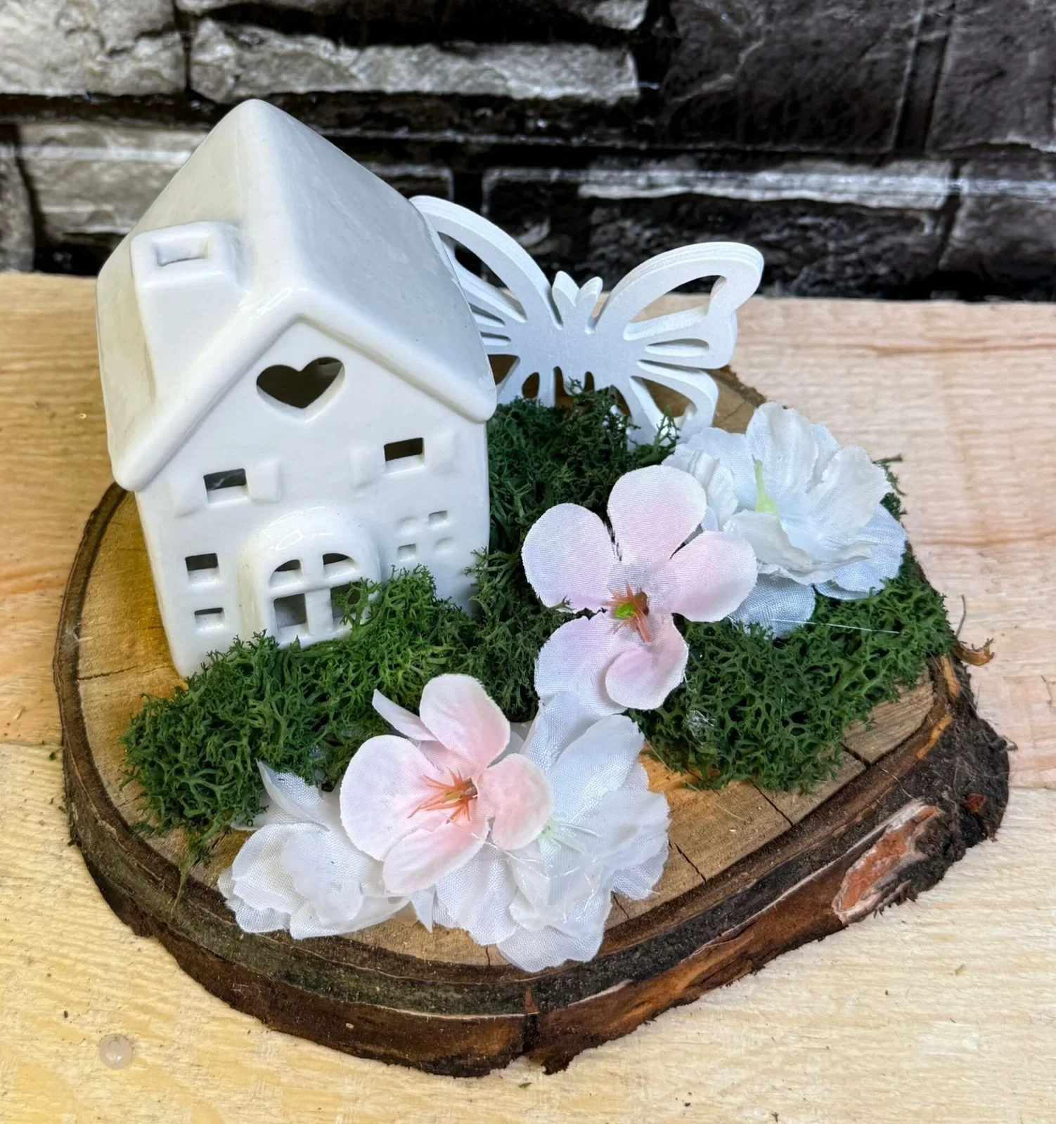 Frühlingsarrangement mit Keramikhaus und Blüten